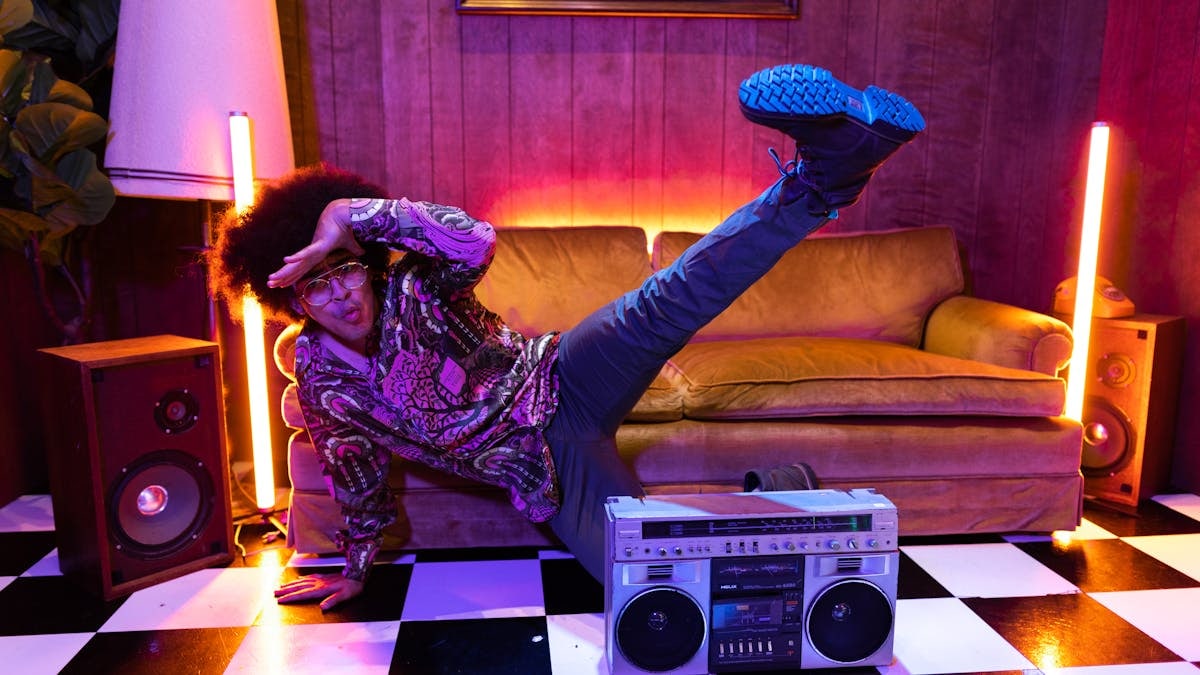 A vibrant retro-themed studio scene featuring a person dancing energetically with a vintage boom box.