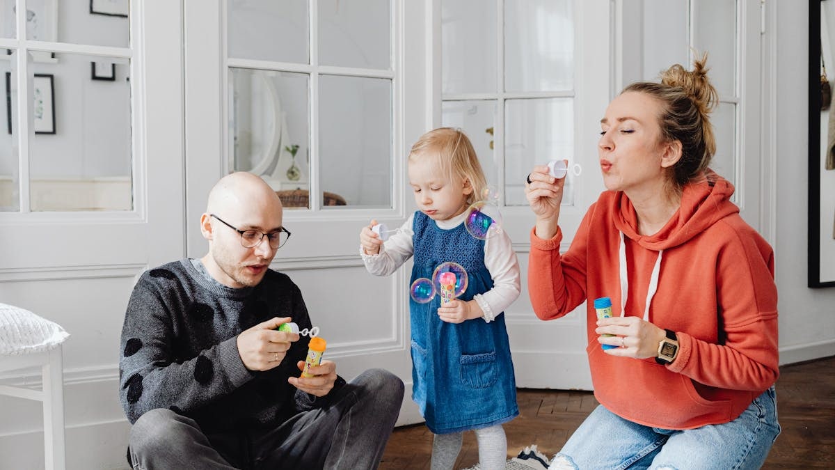 Family enjoying quality time blowing bubbles indoors, capturing joyful moments.